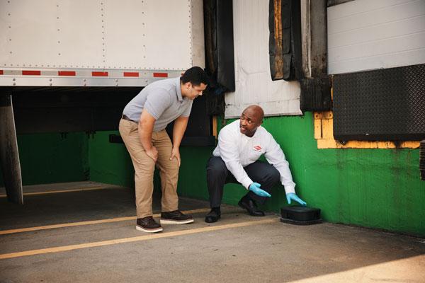 An Orkin Pro discussing the placement of a rodent trap on a loading dock with a customer