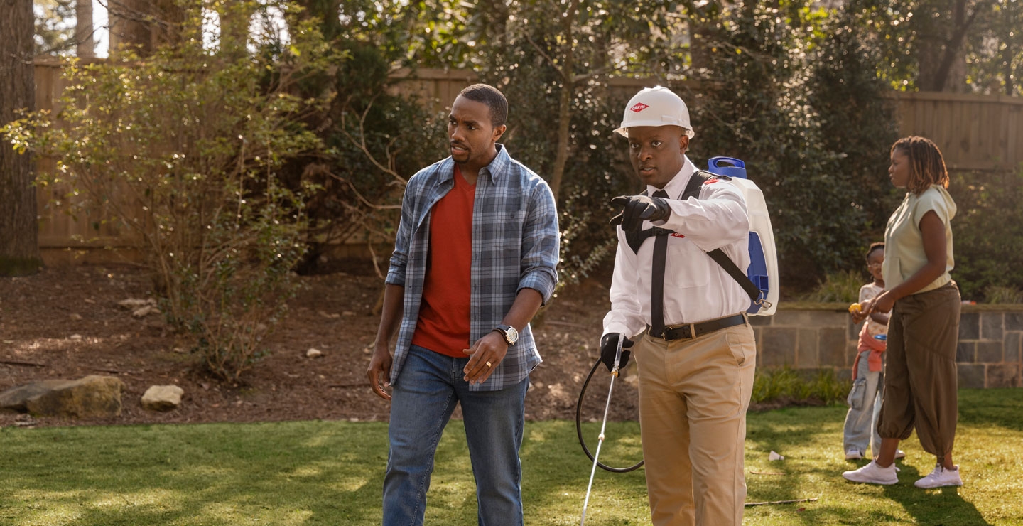 An Orkin Pro speaking with customers in their backyard