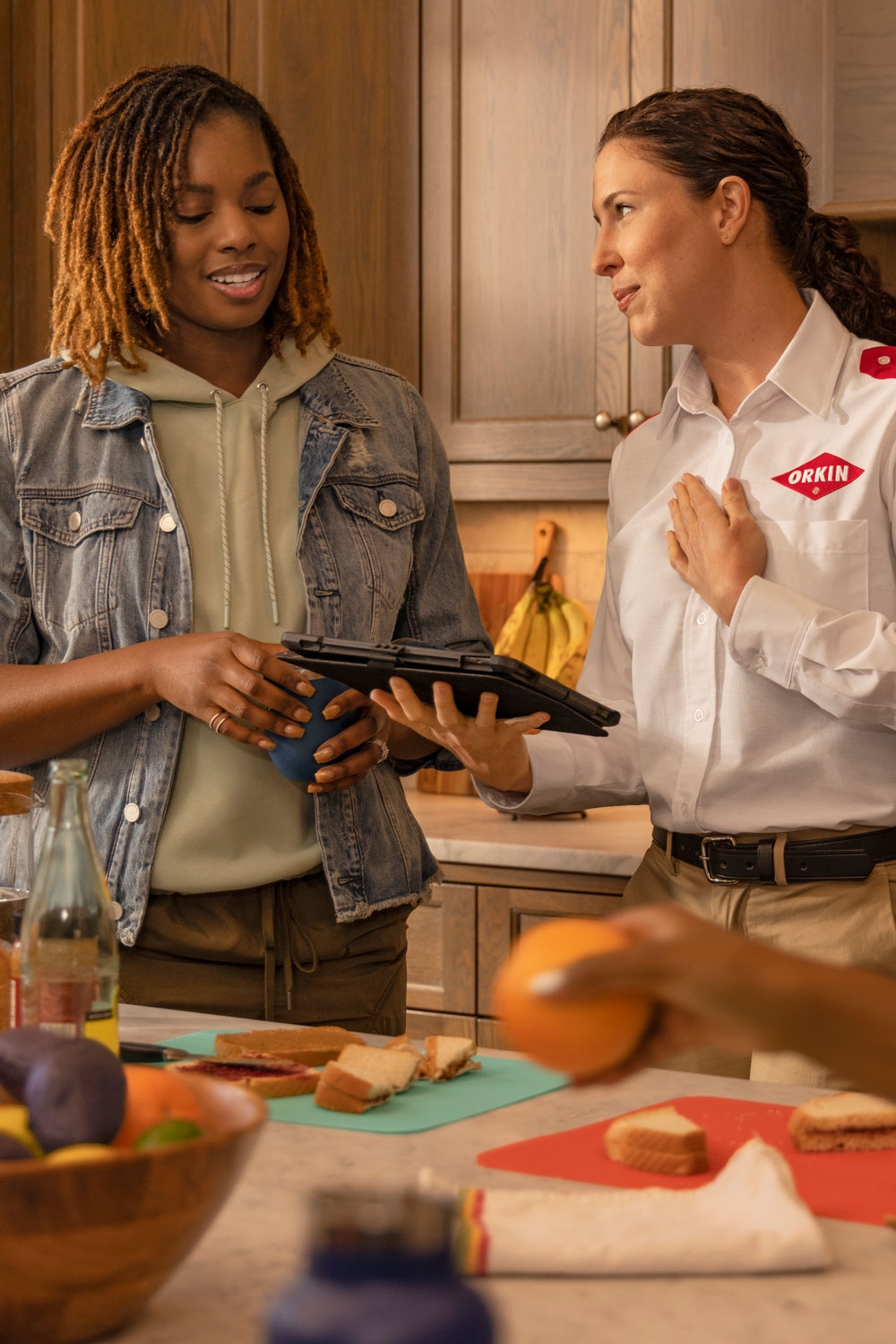 An Orkin Pro discussing ant control services in a customer's kitchen