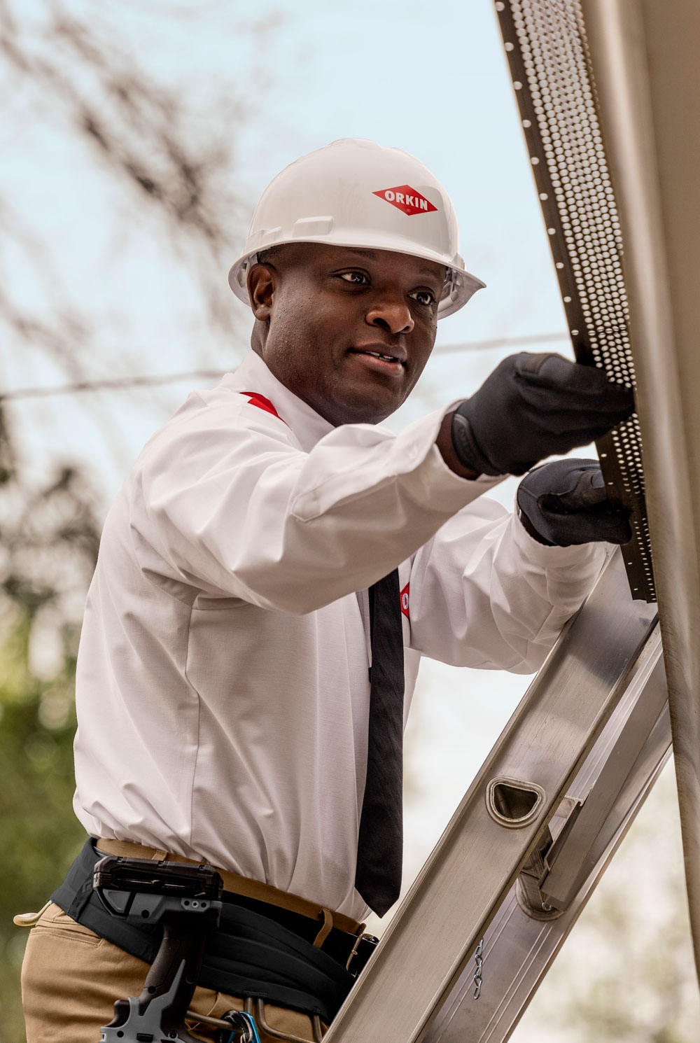 An Orkin Pro installing a leaf stopper to a customer's gutters