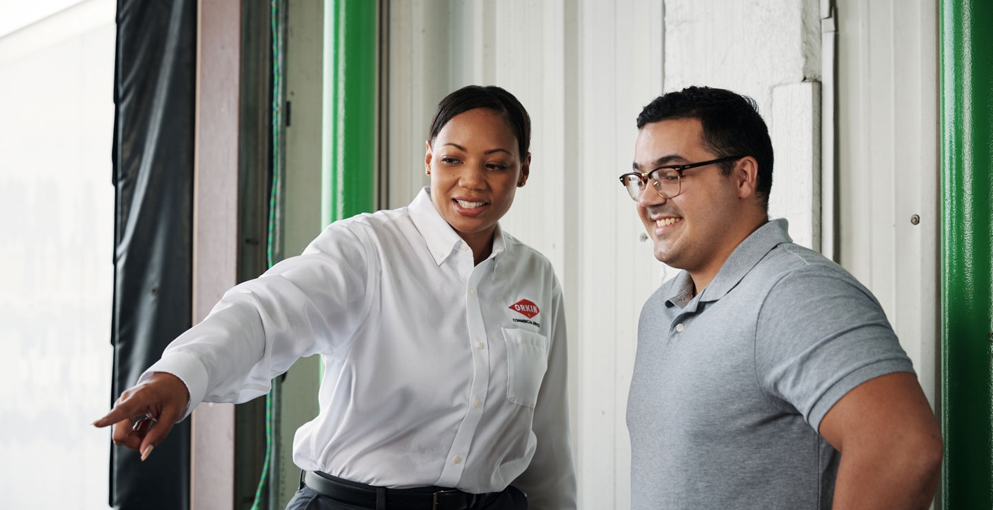 An Orkin Pro pointing to a spot in a warehouse