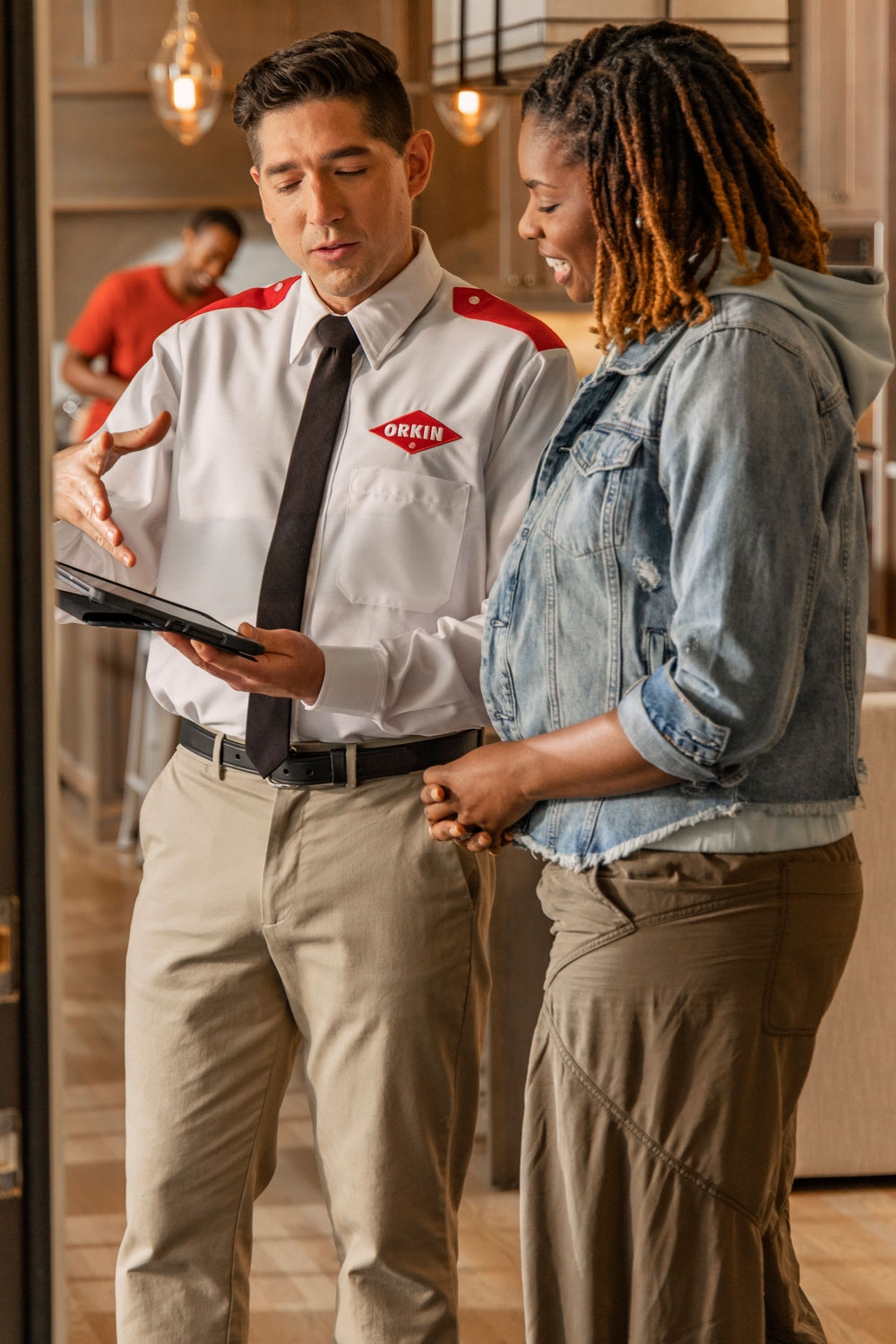 An Orkin Pro speaking with a customer in her living room