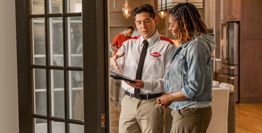 An Orkin Pro speaking with a customer in her living room