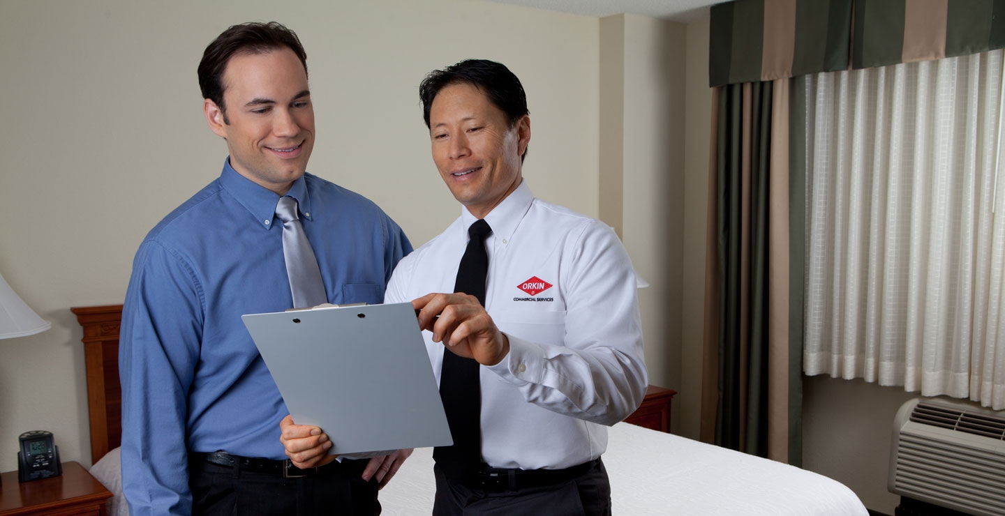 An Orkin Pro talking to a client in a hotel room