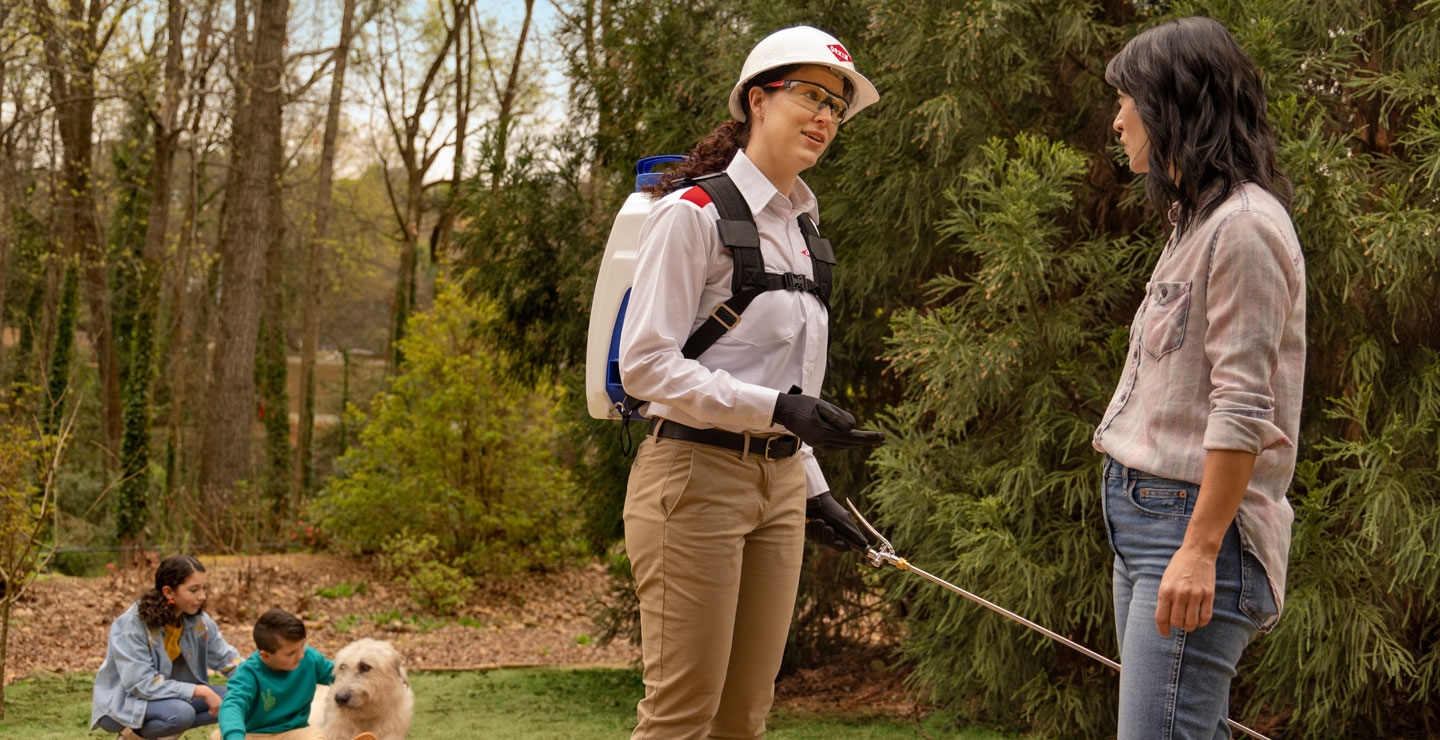 An Orkin Pro discussing mosquito control services with a client in their backyard